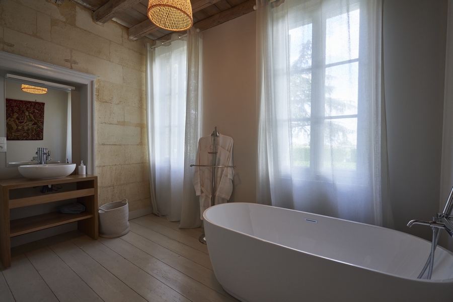 Salle de bains avec baignoire ovale ancienne, peignoirs, double vasques